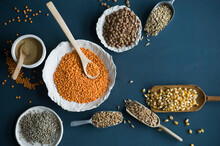 Red lentils, brown lentils, amarant, wheat, spelt wheat and corn in bowls and on spoons
