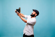 Bearded Young Man In Studio Taking Selfie With Instant Camera