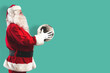 Santa Claus with a soccer ball in his hands isolated on a mint colored background