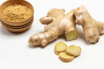 Raw ginger root. Dry ginger powder in bowl.