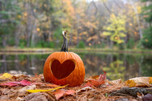 Pumpkin Carved With A Heart Shape On A Bed Of Leaves In Autumn