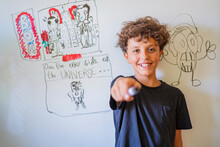 Portrait Of Happy Boy In Front Of Drawing On A Whiteboard