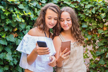 Young Girls Using Smartphone On Ivy Background
