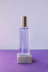 Wall Mural - Cosmetic water or hydrolat in glass bottle on podium on purple tablle. Natural cosmetics concept. Mock up