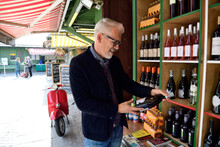 Mature Man Choosing Bottle Of Wine At A Wine Shop