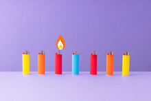 Row Of Colorful Lighters Against Purple Background