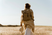Rear View Of Female Traveller With Backpack On Meadow