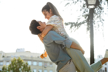 Happy young multiracial couple with korean man and european female hugging and lifting smiling at each other