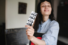 Woman Holding Photos Of Herself With Her Boyfriend