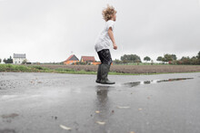 Boy Jumping Into A Puddle