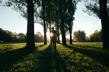 Silhouette Of Man Walking In A Park At Sunrise