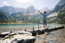 Austria, Tyrol, Man Standing On Tree Trunk At Lake Seebensee