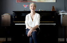 Portrait Of Laughing Woman Sitting In Her Music Room In Front Of Piano
