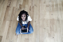 Portrait Of Smiling Woman Sitting On The Floor With Digital Tablet