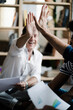 © Giorgio Fochesato/Westend61 - Happy business team sitting on floor with documents high fiving