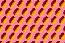 Pattern Of Yellow Plastic Corn Cobs Against Pink Background