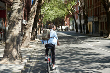Back View Of Young Man Riding Rental Bike On Bicycle Lane, London, UK