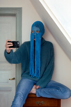 Portrait Of Young Woman Wearing Crochetedblue Headdress With Fringes Taking Selfie With Smartphone