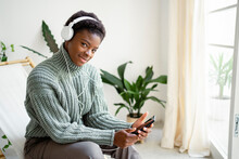 Woman With Mobile Phone Listening Music Through Headphones In Living Room