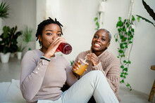 Multi-ethnic Female Friends Drinking Juice While Sitting In Living Room