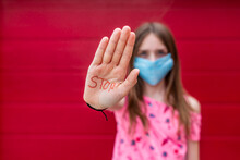 Girl With Face Mask Showing Palm Of Her Hand, Saying Stop