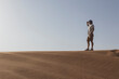 © SERGIO NIEVAS/Westend61 - Male tourist shielding eyes while standing on sand dune against clear sky at Dubai, United Arab Emirates