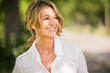 © UWE_UMSTAETTER/Westend61 - Thoughtful mature businesswoman smiling outdoors during sunny day