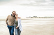 © UWE_UMSTAETTER/Westend61 - Cheerful couple laughing while walking against sea during sunset