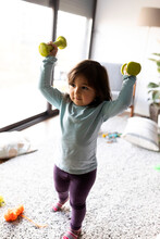 Portrait Of Little Girl Exercising With Dumb Bells At Home