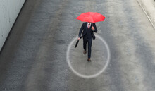 Businessman Walking Along Street With Red Umbrella In Hand