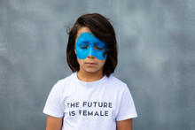 Portrait Of Boy With Painted Blue Mask On His Face Wearing T-shirt With Imprint 'The Future Is Female'