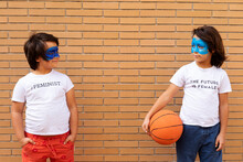 Portrait Of Two Brothers With Painted Blue Masks On Their Faces Wearing T-shirts With Feministic Imprints