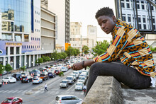 Young Man In Patterned Shirt Sitting On Roof Terrace In The City, Maputo, Mozambique
