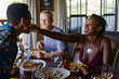 © victor espadas/Westend61 - Smiling young woman feeding friend while sitting at dining table