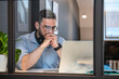 © Westend61 - Thoughtful handsome male professional looking at laptop seen through glass wall in creative coworking office