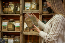Woman With Protective Face Mask Holding Spice Jar At Store