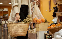 Herbs And Orange Fruit In Bag Held By Woman At Store