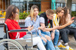 © William Perugini/Westend61 - Young woman with friends busy in using smart phones while sitting outdoors