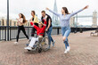 © William Perugini/Westend61 - Carefree men and women with disabled female friend spending leisure time in city, London, UK