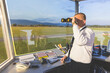 © William Perugini/Westend61 - Pilot standing in control tower, using binoculars