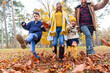 © William Perugini/Westend61 - Smiling family playing with fallen leaf while walking in forest