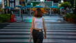 Young beautiful Asian woman walking on street crosswalk in the city and looking at crowd of people and illuminated night lights. Pretty girl enjoy urban outdoor activity lifestyle and city nightlife.