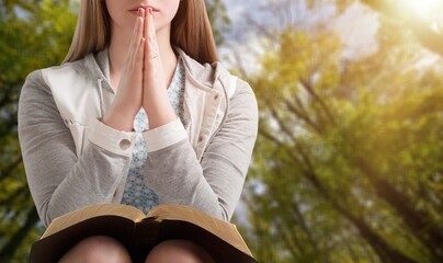 Sticker - Hands folded praying over a Bible book.