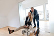 © KNSY/Westend61 - Playful businessman pushing businesswoman on toy car in office