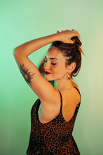 Portrait Of Tattooed Young Woman With Eyes Closed Against Green Background