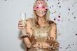© IVAN GENER/Westend61 - Senior woman wearing golden dress and flmingo shaped glasses, celebtraing New Year's Eve