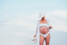 Pregnant Woman With A Drawn Heart On Her Belly Holding A Teddy Bear