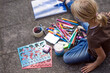 © Jana Fernow/Westend61 - Girl sitting on pavement with many drawing materials