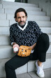 © Johanna Lohr/Westend61 - Portrait of fashionable mature man sitting on stairs with baseball catcher and ball