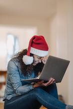Woman With Santa Hat Looking For Presents Online, Using Laptop